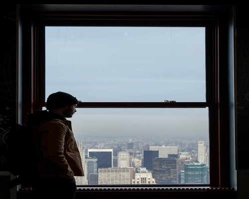 Person looking thoughtfully out the window at the cityscape